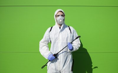 Portrait of person in chemical protection suit holding sprayer for disinfection to stop spreading corona virus.